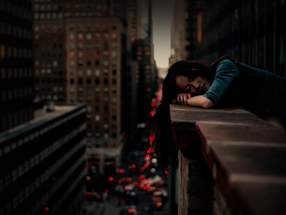 Mujer se recuesta en el borde de la terraza de un edificio