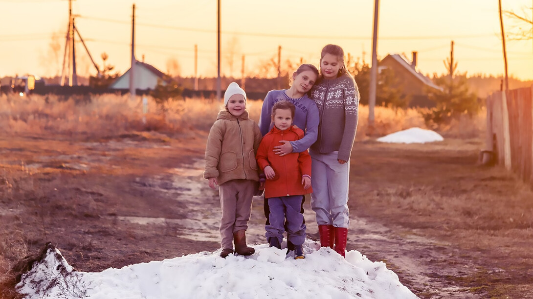 Two children stand on snow-covered ground during the daytime, playing on a snowdrift at a farm near Moscow, USSR
