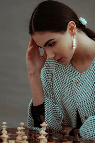 A contemplative woman of diverse ethnicity pondering her next chess move