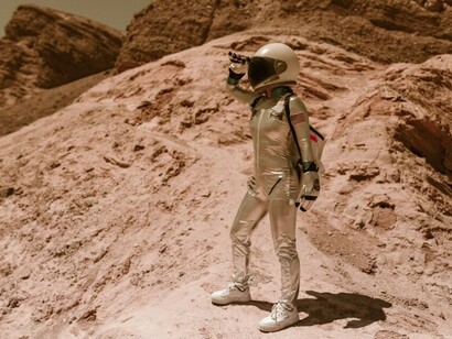 An astronaut standing on a rock on Mars, observing the red terrain and distant horizon