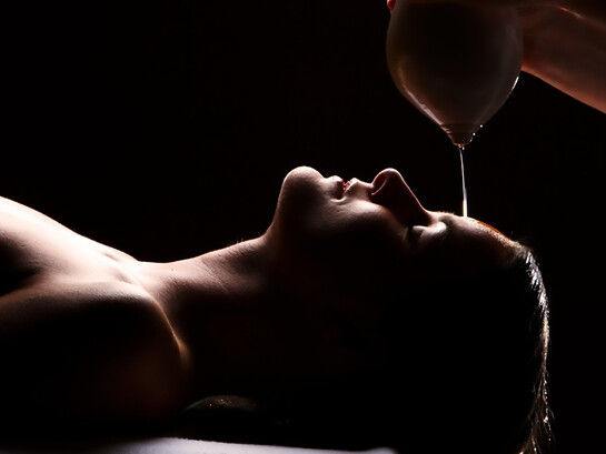 Shirodhara oil therapy, a soothing Ayurvedic treatment, performed in an Indian spa to promote deep relaxation and inner balance