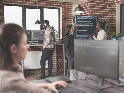 Developers and database admins using AI to analyze and compare coding errors on a wall-mounted screen
