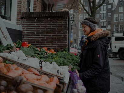 A woman food shopping at the greengrocer is examining the produce with glee 