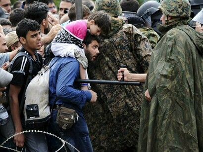 Un policía amenaza a un refugiado sirio