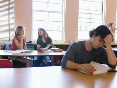 Two women are talking about a male student at school who often appears lonely