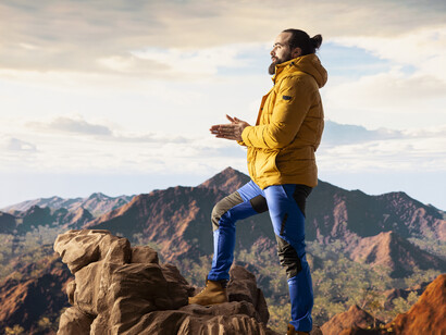 A lone traveler stands on a mountain summit, taking in the stunning view of the surrounding peaks