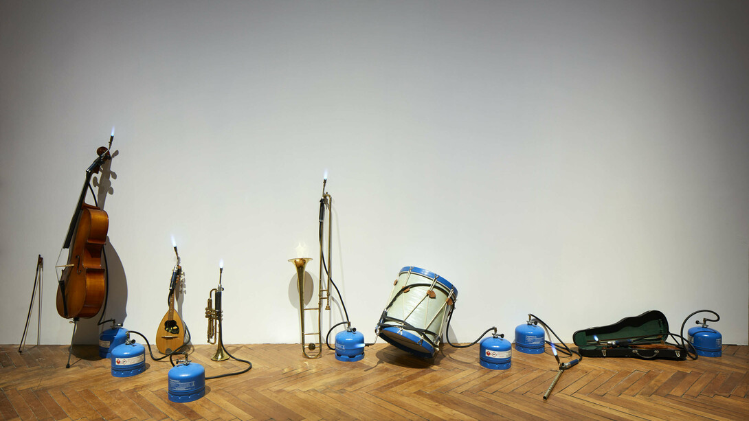 Jannis Kounellis, Senza titolo (1980), flauto, violino, tamburo, tromba, cornetta, violoncello, mandolino, bombola a gas, fiamme, foto Agostino Osio - Alto Piano, Courtesy Fondazione Prada