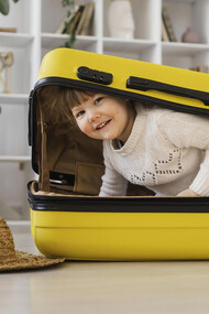 Smiling toddler sitting playfully inside an open suitcase