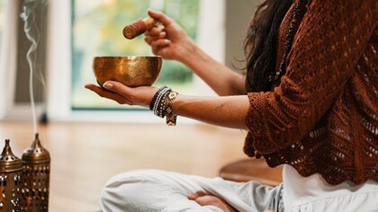 Woman in brown knit sweater holding brown ceramic cup making musical notes