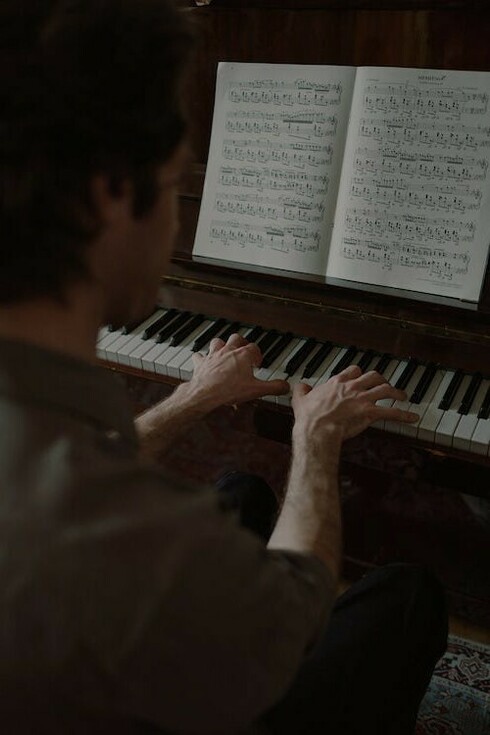 Un uomo suona al pianoforte leggendo uno spartito