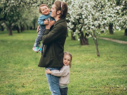 Daughter hugging father as he holds a child