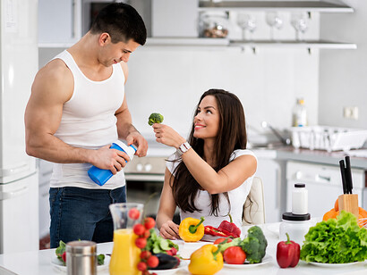 Fit couple enjoying a healthy vegan meal together in a modern kitchen after a workou