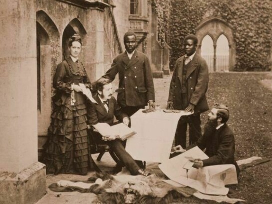 Agnes and Thomas Livingstone, daughter and son of David Livingstone, Abdullah Susi, James Chuma and Rev Horace Waller at Newstead Abbey, Nottingham, with the journals, maps and plans made by the late David Livingstone, 1874