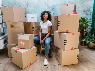 A happy woman sitting on the floor among moving boxes, marking a new beginning