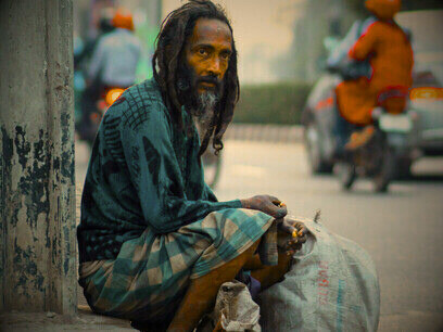 Un homme assis au bord de la route, symbole de ces existences devenues invisibles dans des sociétés où la pauvreté est perçue comme une faute individuelle