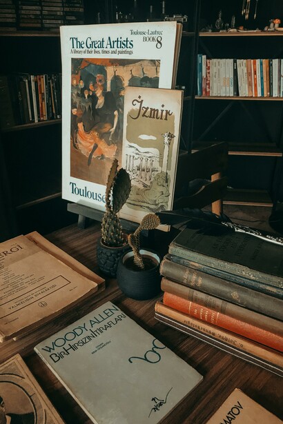 A collection of old books on a wooden desk, one of them written by Woody Allen