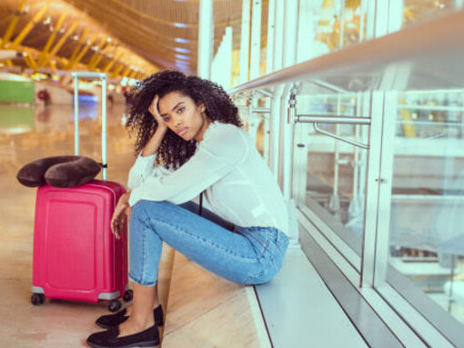 At the airport, a woman sits by the window with her laptop—an expat preparing for her next journey