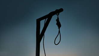 A rope tied to a wooden post in front of a building, resembling a gallows