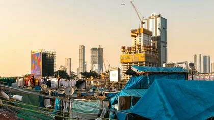 Makeshift homes in the shadow of modern high-rises, symbolizing the gap between economic success and social equality