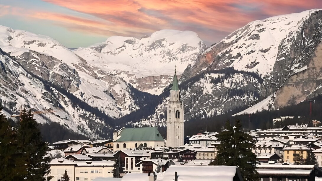 Cortina d'Ampezzo, Veneto, Italia. Cortina deve gran parte della sua fama alla bellezza naturale delle Dolomiti circostanti. Le maestose vette rocciose, i boschi di abeti e i prati alpini creano uno scenario spettacolare che cambia con le stagioni. Durante l'inverno, le montagne sono coperte da un candido manto di neve, offrendo uno spettacolo mozzafiato che incanta gli occhi di chiunque
