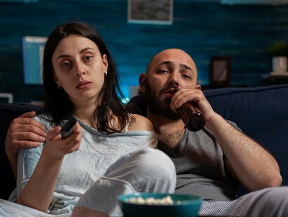 Uomo e donna annoiati davanti all TV: "Niente binge watching, quindi, niente social network, niente gratificazioni immediate. È necessario sperimentare il vuoto per poterlo riempire con un significato profondo e non solo tapparlo in una qualche maniera"