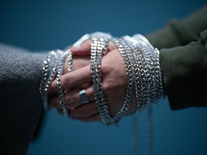 Two hands joined through loosely draped chains, representing acceptance without remaining emotionally bound