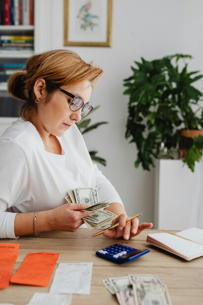 A woman calculating expenses at a kitchen table