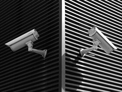Dos cámaras de vigilancia apuntan en direcciones opuestas sobre la fachada de un edificio