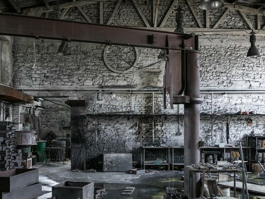 A forgotten factory space with high ceilings and exposed framework, representing the potential for converting industry into habitation