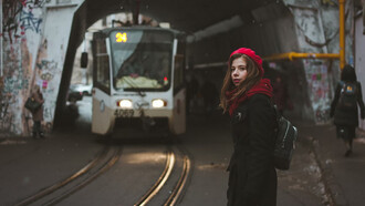 A woman standing in front of a train in a tunnel, ready for her next adventure as a traveler