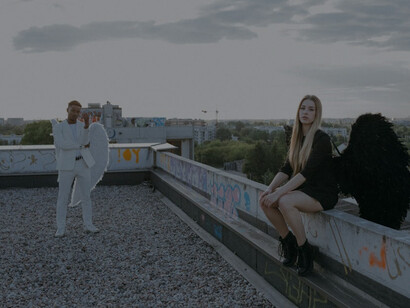 A man and woman in black and white angel costumes, embodying the dichotomy of good and evil