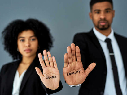 An African American woman and man raising their hands, each displaying "gender equality" to advocate for wage equality