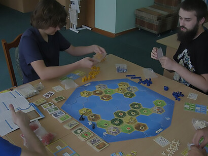 Young boys immersed in the strategic thrill of playing the Settlers of Catan board game, showcasing the excitement and engagement of Catan gameplay