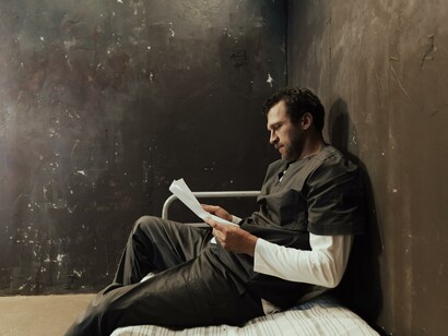 A man sat alone in a cell reading 