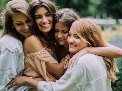 A group hug from four people who are showing the camera that their friendship is real and not fake