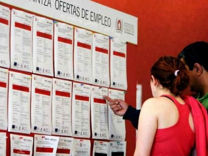 Dos jóvenes consultan un tablón de ofertas de empleo