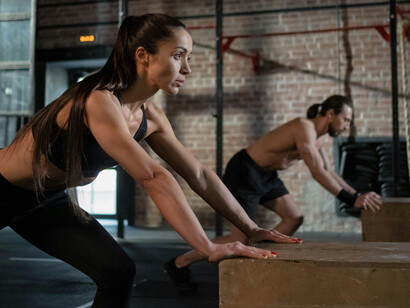 A man and woman practice plyometric exercises as part of their HIIT fitness routine