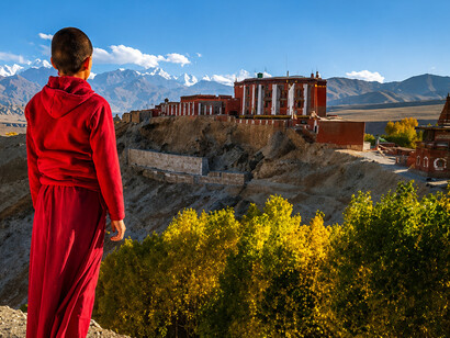 A novice Tibetan monk gazes across the dramatic landscape near Tsarang Village in Upper Mustang, Nepal