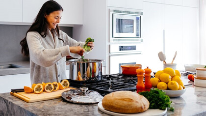 Radiate joy in the kitchen as you capture the delightful moment of a woman smiling while she prepares a meal