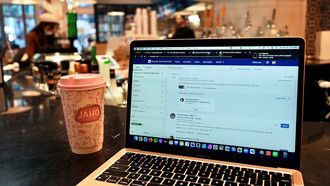 A laptop rests on a table, ready for work in a cozy café setting
