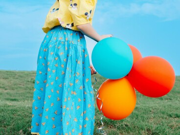 A young girl holding tightly to several balloons as she stands alone, representing the instinct to cling to what makes us feel safe