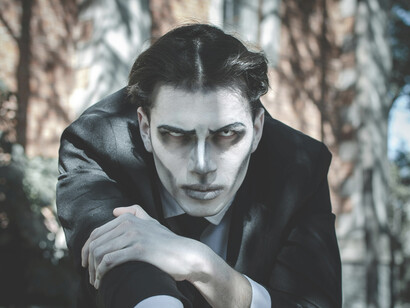 A dramatic Gothic portrait of a man wearing makeup, illuminated by sunlight