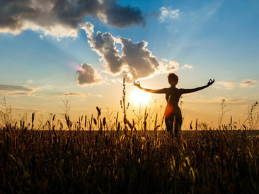 Silhouette of a girl practicing yoga in a serene field at sunrise, embodying mindfulness and meditation as she connects with nature
