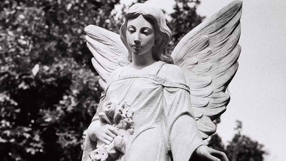 A black and white photograph of an angel statue in a cemetery