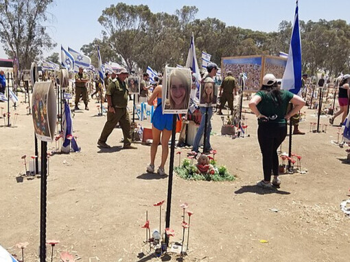 Vue élargie du mémorial du festival Nova, avec des dizaines de portraits alignés, entourés de symboles de deuil et d'hommage national, commémorant les victimes du 7 octobre 2023