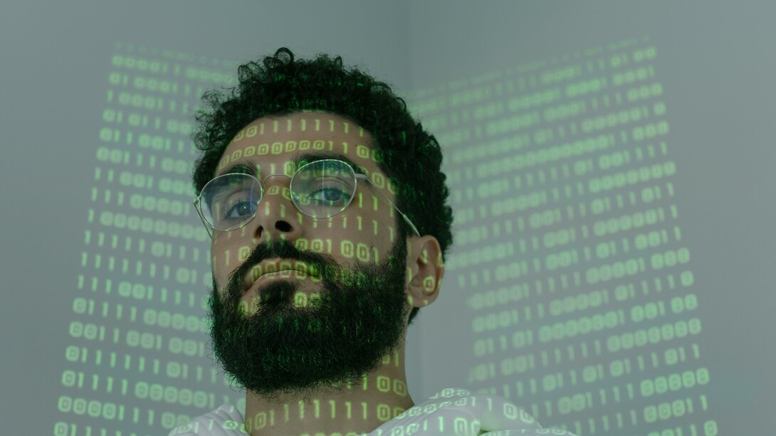 A man with computer code shone over his face
