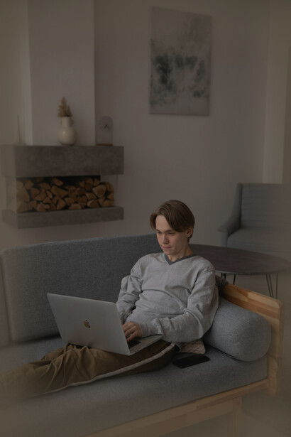 Un muchacho usando su computadora en el sillón. El 31% de la población mundial no alcanzó los niveles recomendados de actividad física en 2022