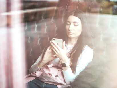 Mujer sentada en un sofá absorta en su teléfono móvil