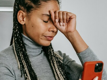 Mulher se incomoda ao observar seu telefone celular. Com o advento das redes sociais, influenciadores e celebridades globais passaram a moldar e reforçar padrões estéticos, muitas vezes estabelecendo ideais que são inatingíveis para a maioria das pessoas