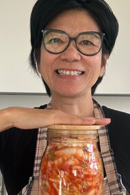 Debout, un bocal entre les mains, Kim Chi Pho tient bien plus qu’une recette : un fragment d’histoire, patiemment fermenté entre héritage familial et identité retrouvée